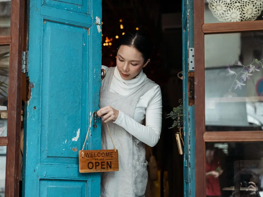 A small business owner turning the open sign on a shop door