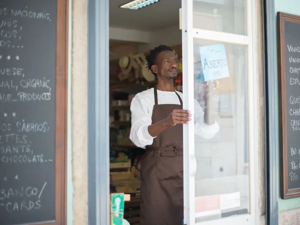 A shop owner opening the door of a grocery store